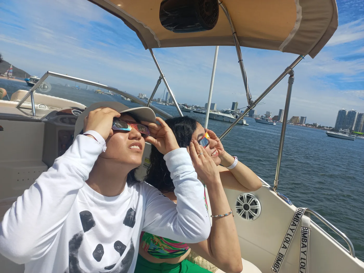 Dos invitadas posando en la cubierta con la ciudad de fondo