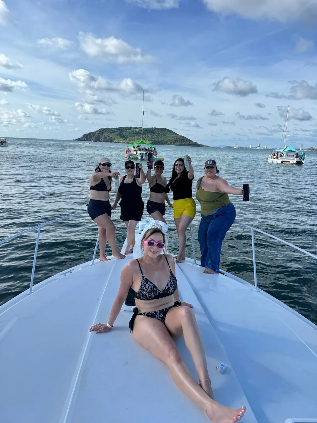 Invitadas conviviendo en la proa del yate frente a la isla