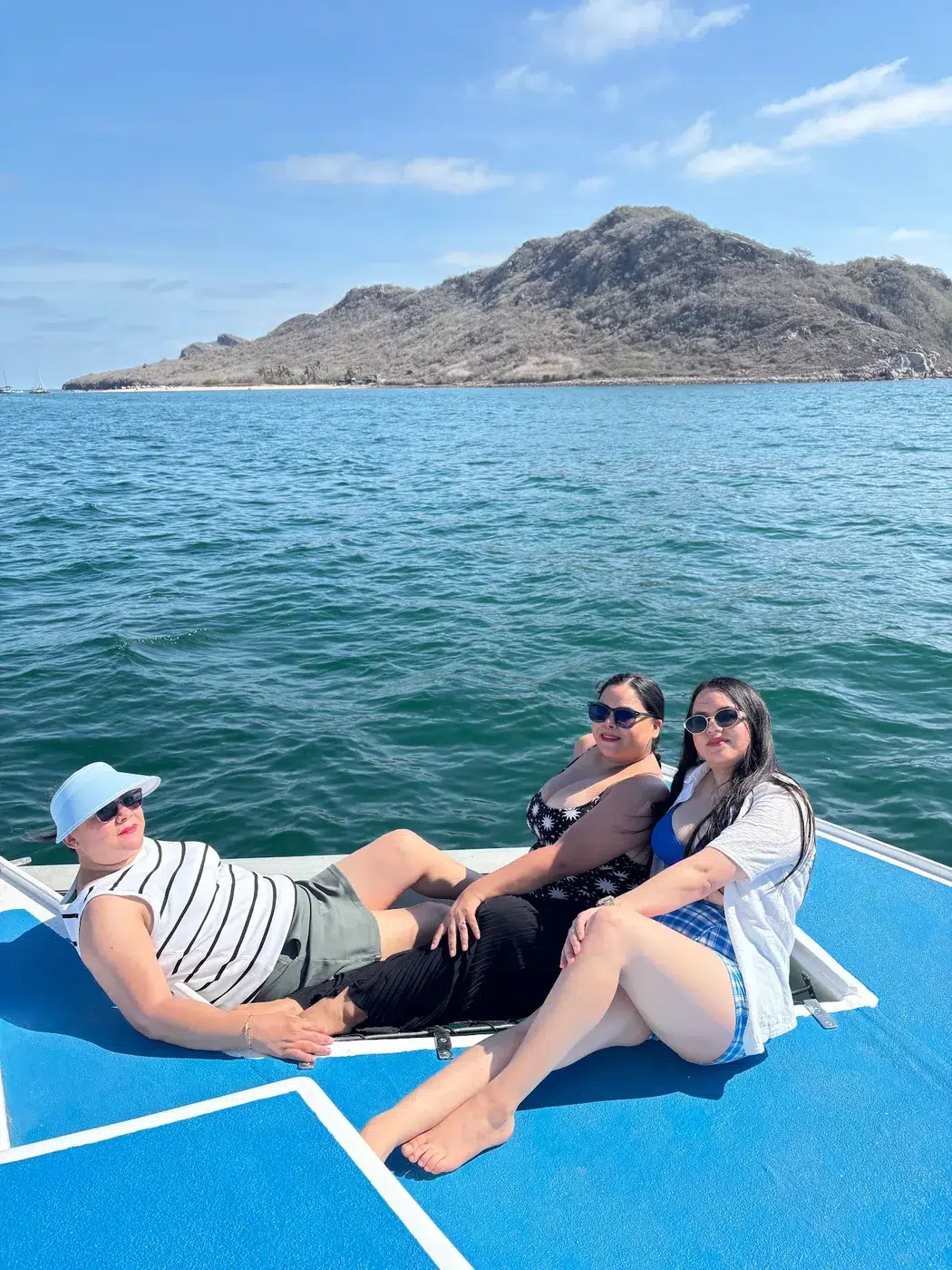 Tres invitadas recostadas en la proa frente a la isla